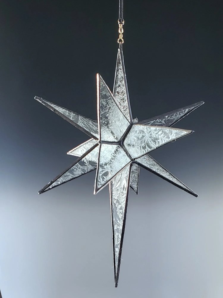 Stunning glass star ornament featuring an intricate design with sharp points and a reflective surface, perfect for holiday decor or festive celebrations.