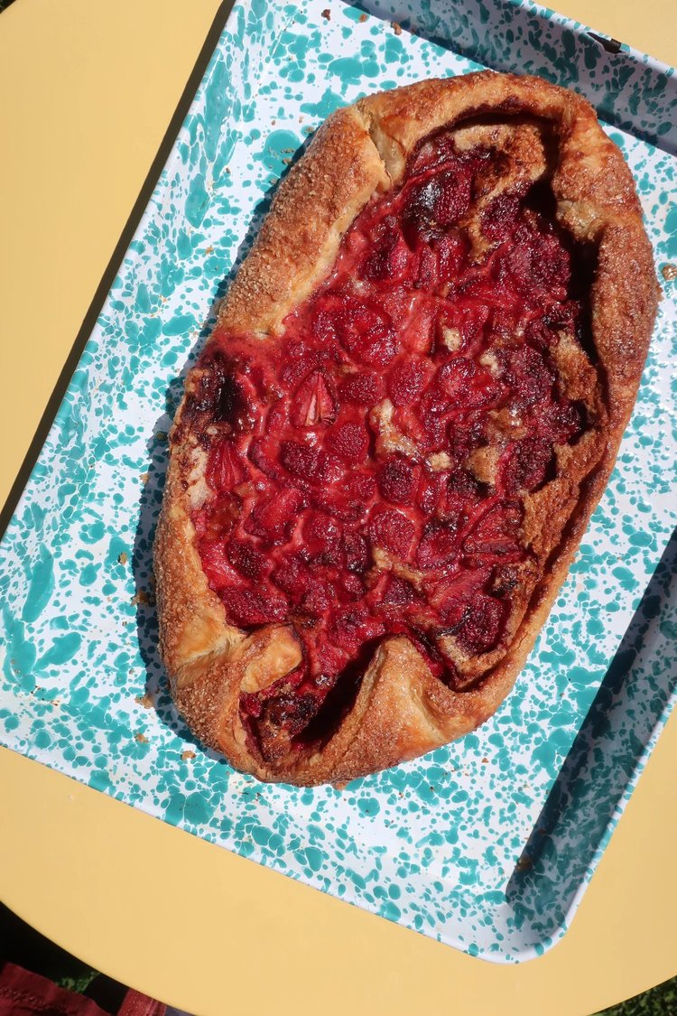 Freshly baked strawberry galette on a turquoise speckled tray, showcasing a golden brown crust filled with vibrant red strawberries. Perfect for dessert or a sweet snack.